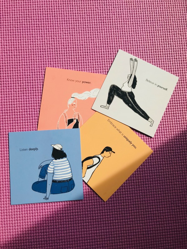 Four square postcards on purple yoga mat. Each postcard has single figure. 