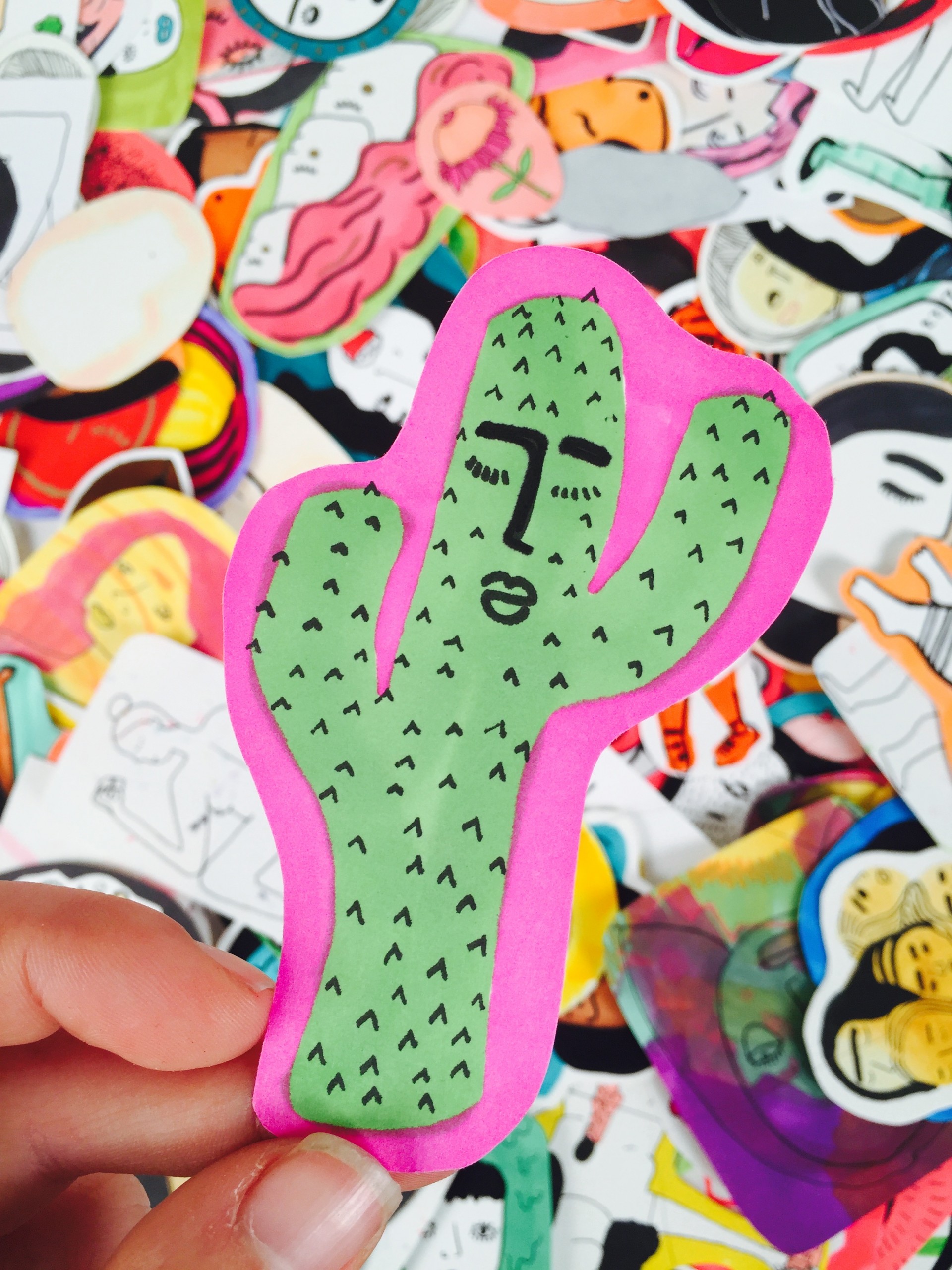 Pile of stickers. Central sticker is cactus with face on it and pink border. 