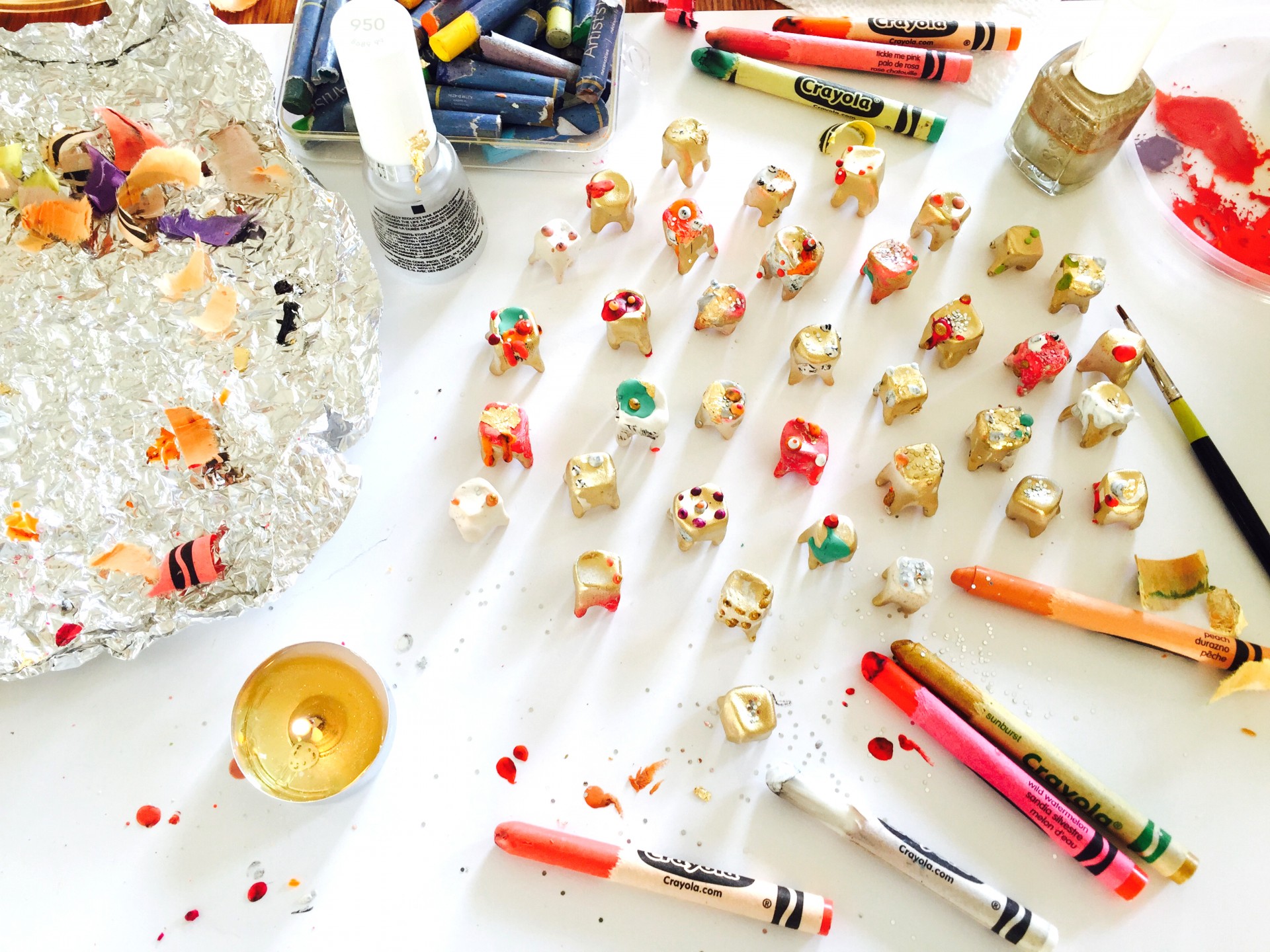 Workspace with crayons, candles and small teeth made out of clay.