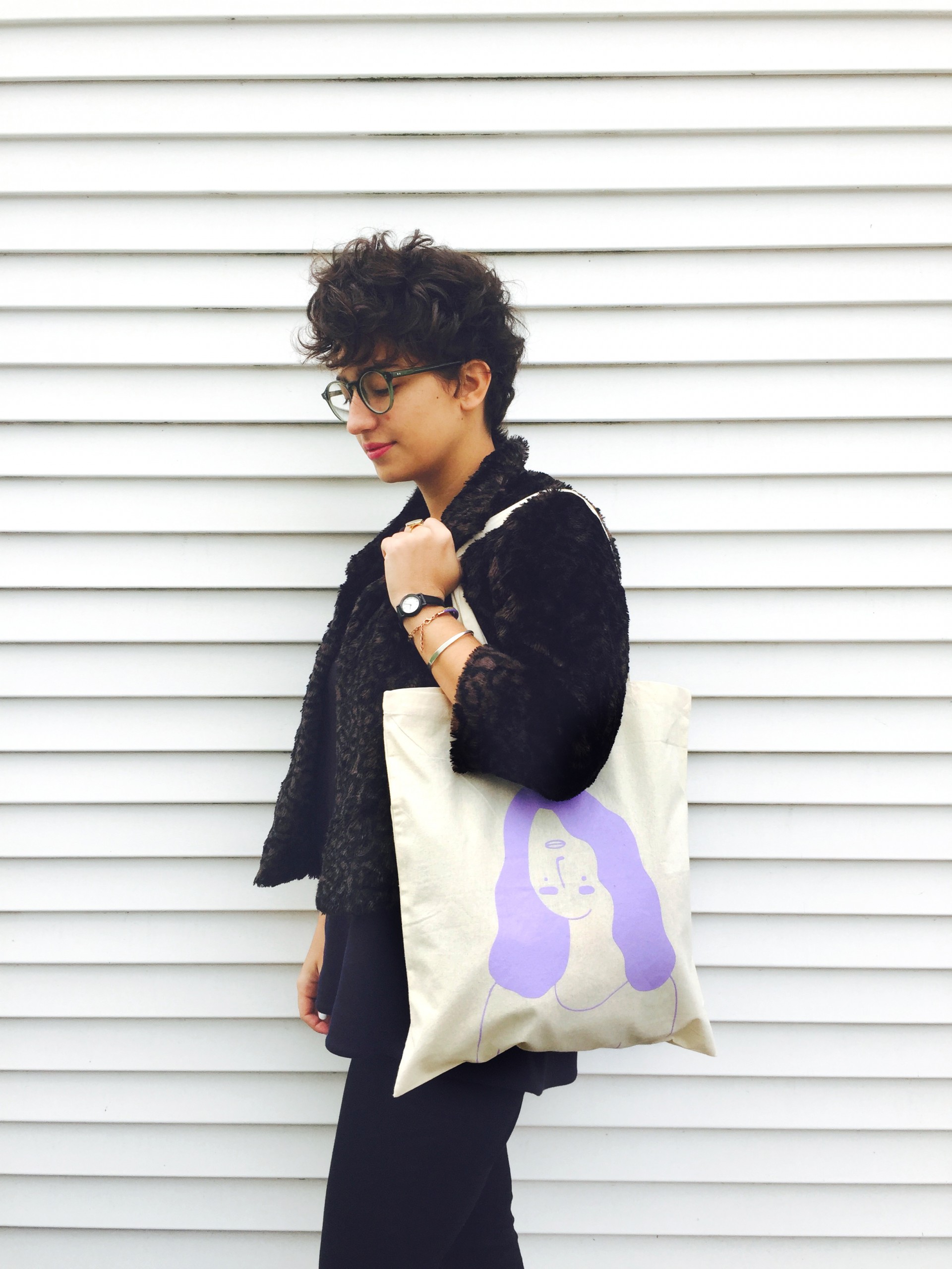 Tan tote bag with a girl printed in lavender whose facial features are upside down 