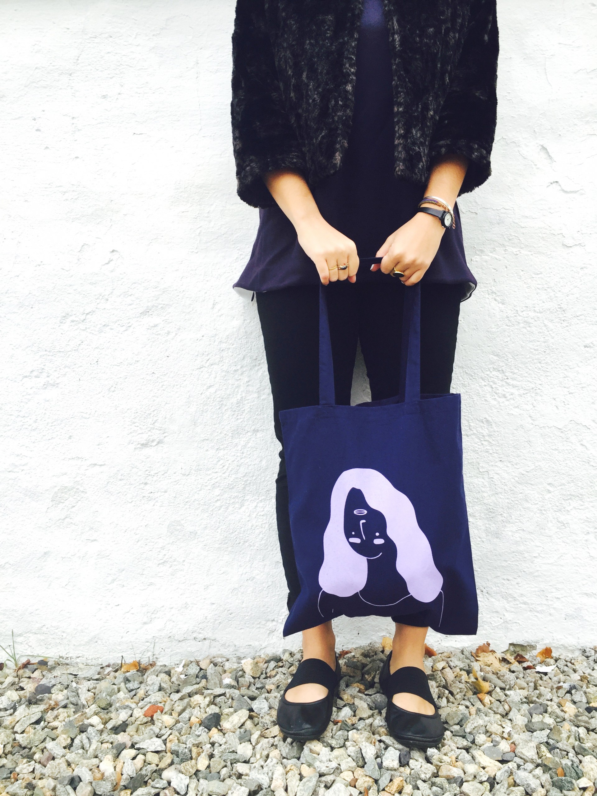 Navy tote bag with a girl printed in lavender whose facial features are upside down 