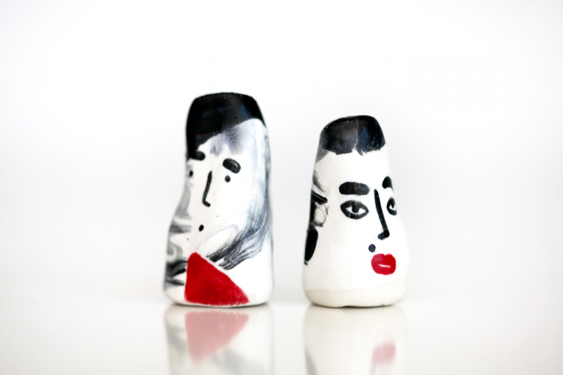 Two porcelain heads facing away from each other on white background. 
